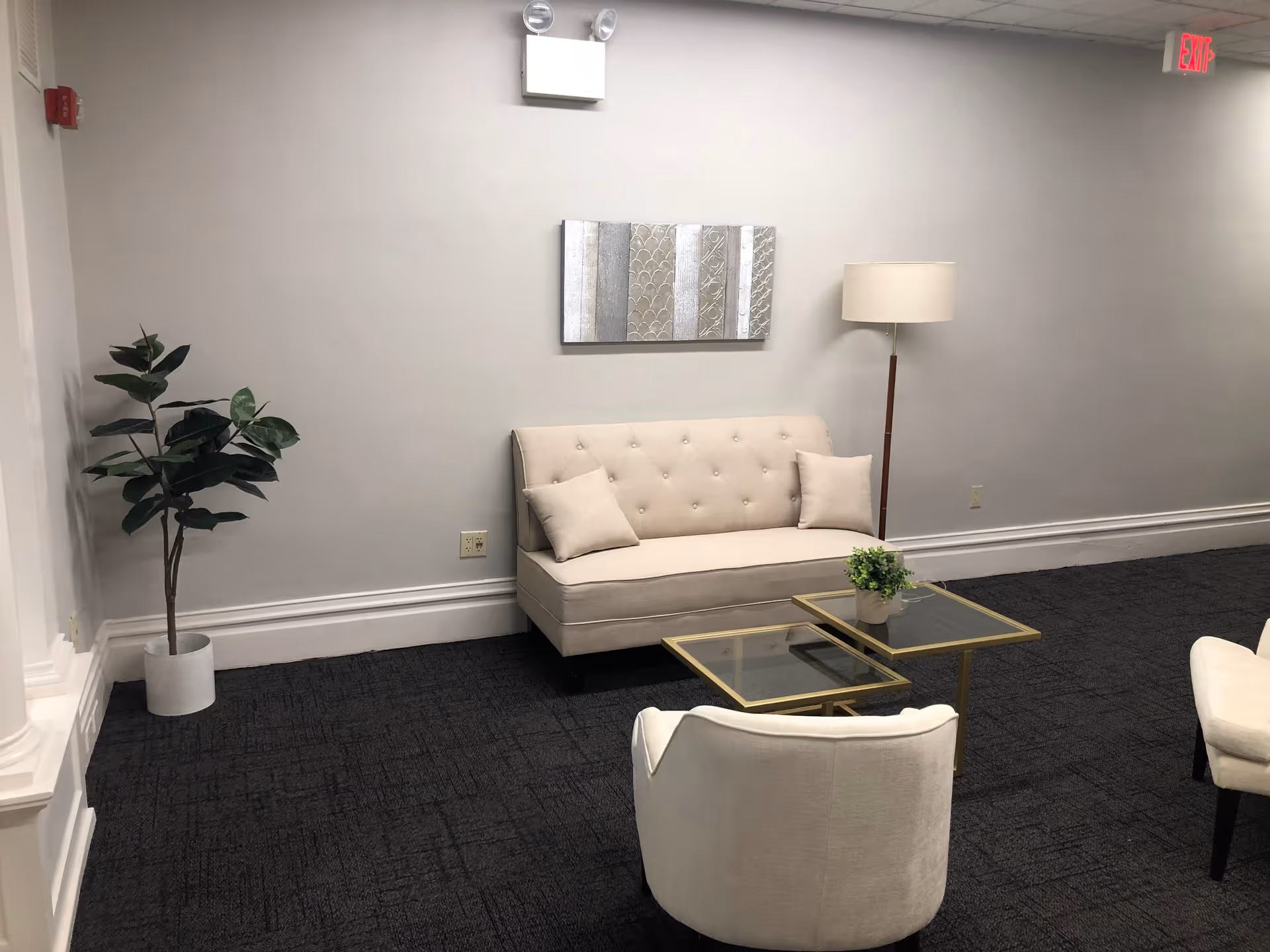Neutral lounge area with beige sofa, glass coffee table, floor lamp, and plant.
