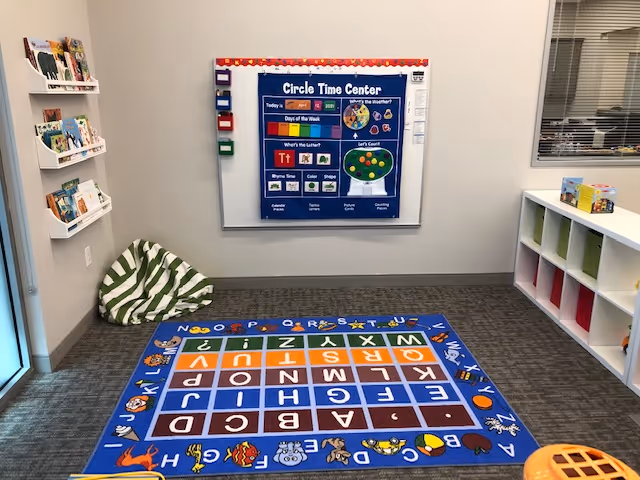 Colorful activity corner in a senior living facility featuring alphabet rug, poster, and cubbies.
