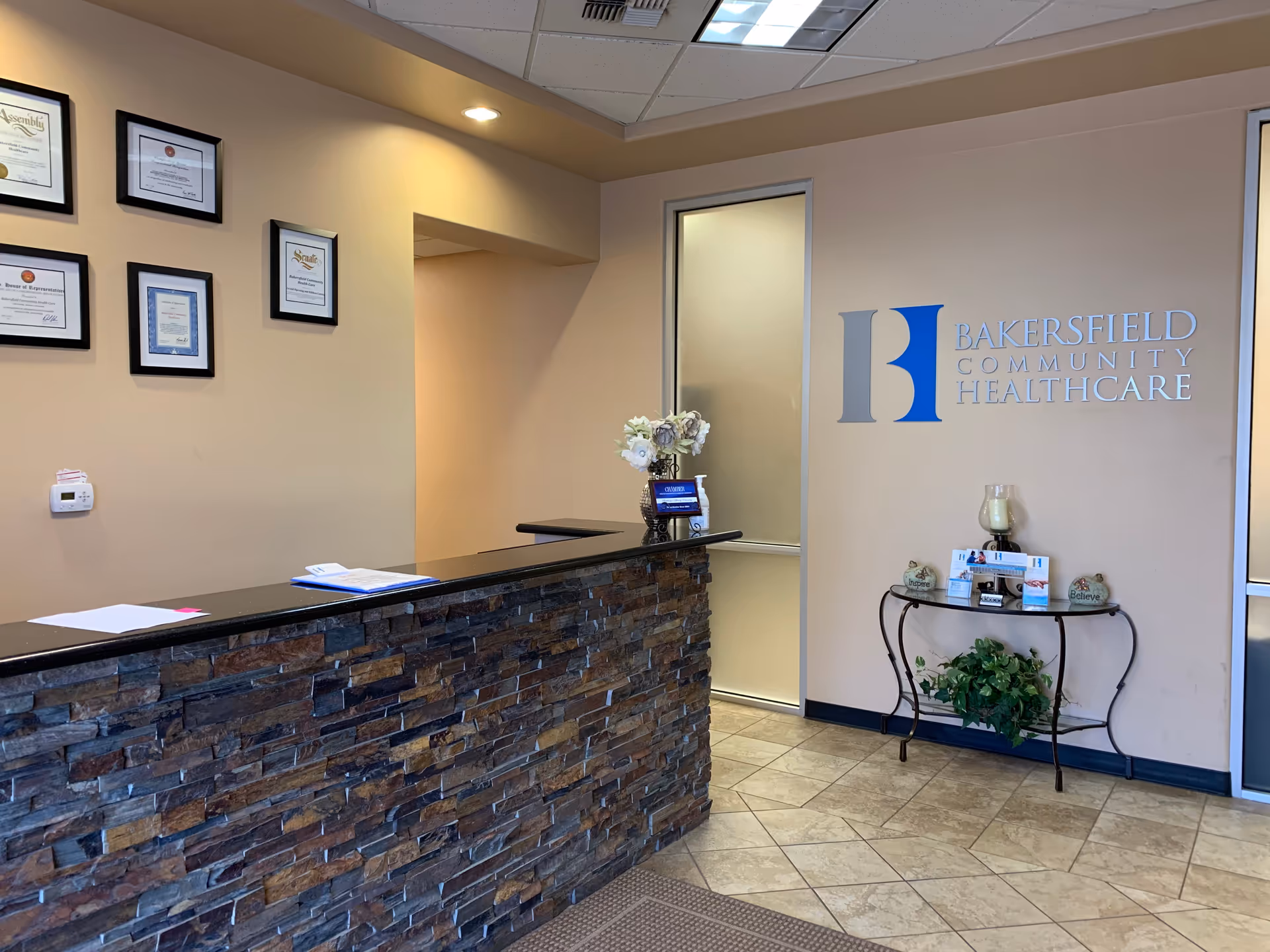 Reception area with stone-front desk and Bakersfield Community HealthCare logo on wall