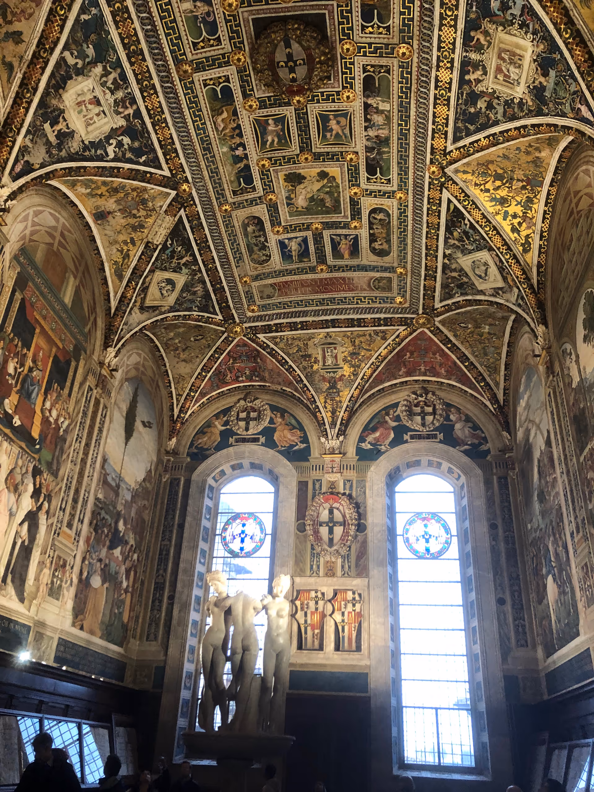 Intricately painted vaulted ceiling with statues and tall stained-glass windows.