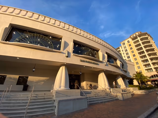 Exterior view of a curved building entrance with arched windows and ramps.