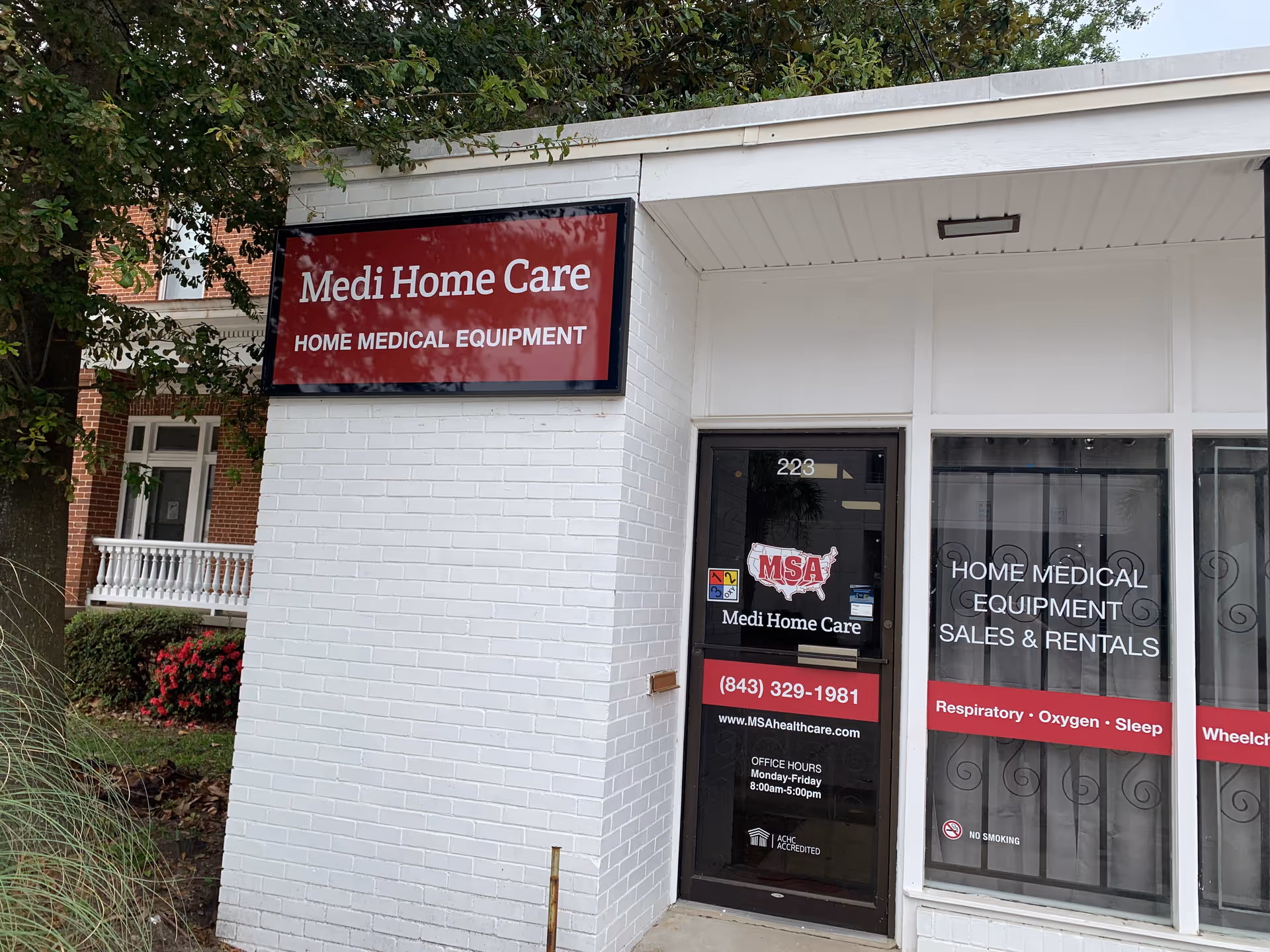 Exterior of Medi Home Care storefront with red sign and glass door reading Home Medical Equipment