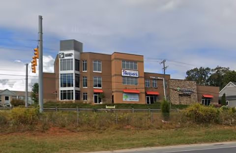 Exterior view of a Senior Helpers senior living building with brick façade and signage.