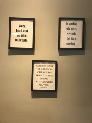 Three framed quotes hang on a beige wall in a hallway.