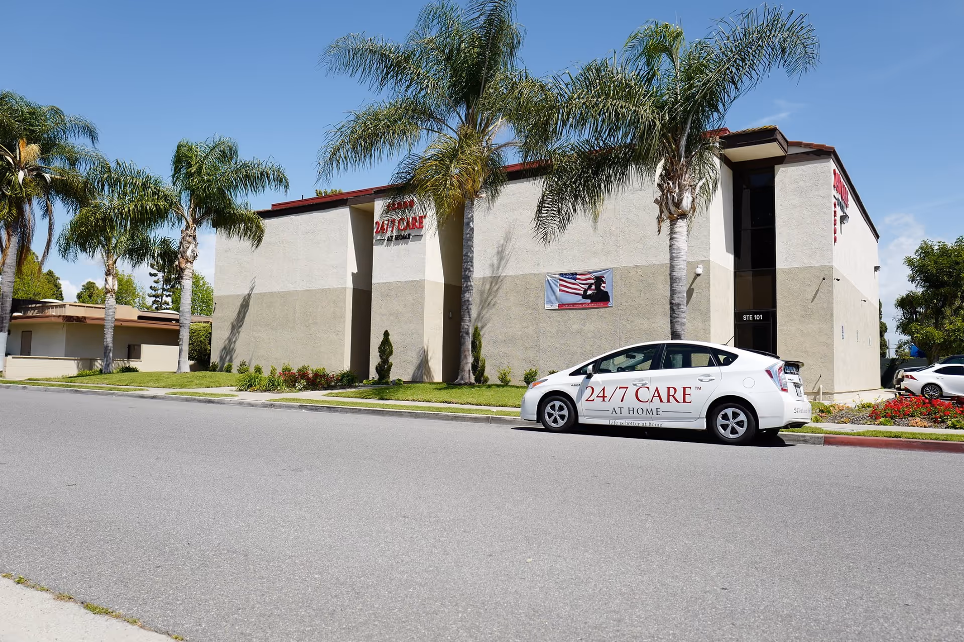 Exterior view of a senior care building with palm trees and a branded car.