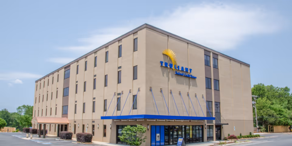 Four-story beige building with blue awning and glass front entrance.