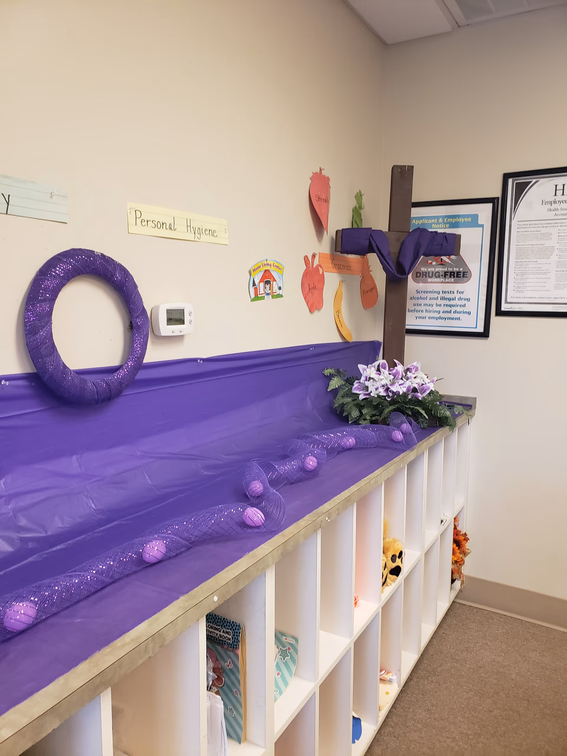 Purple decorations and cubbies line a hallway wall with a Personal Hygiene sign.