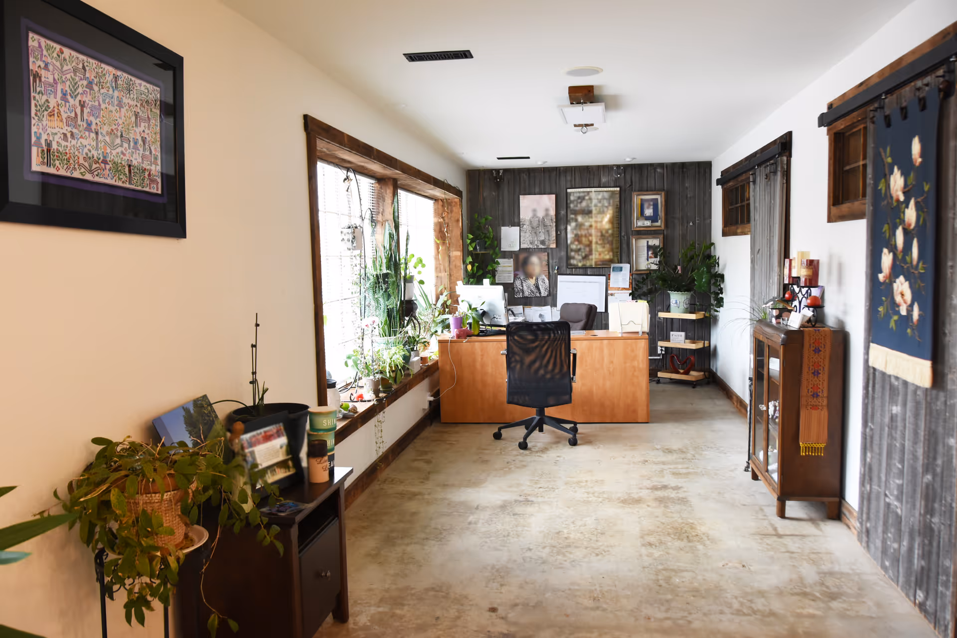 Reception desk, office chair, plants, and framed art in a bright interior space