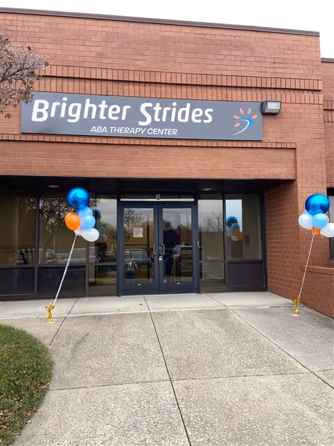 Brick storefront with Brighter Strides ABA Therapy Center sign and blue and orange balloons.