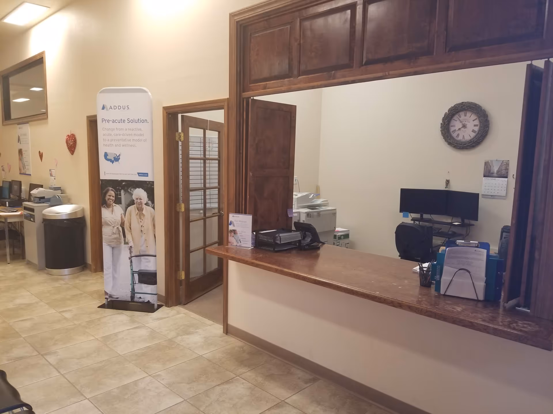 Reception desk in a senior living facility lobby with a wall clock.