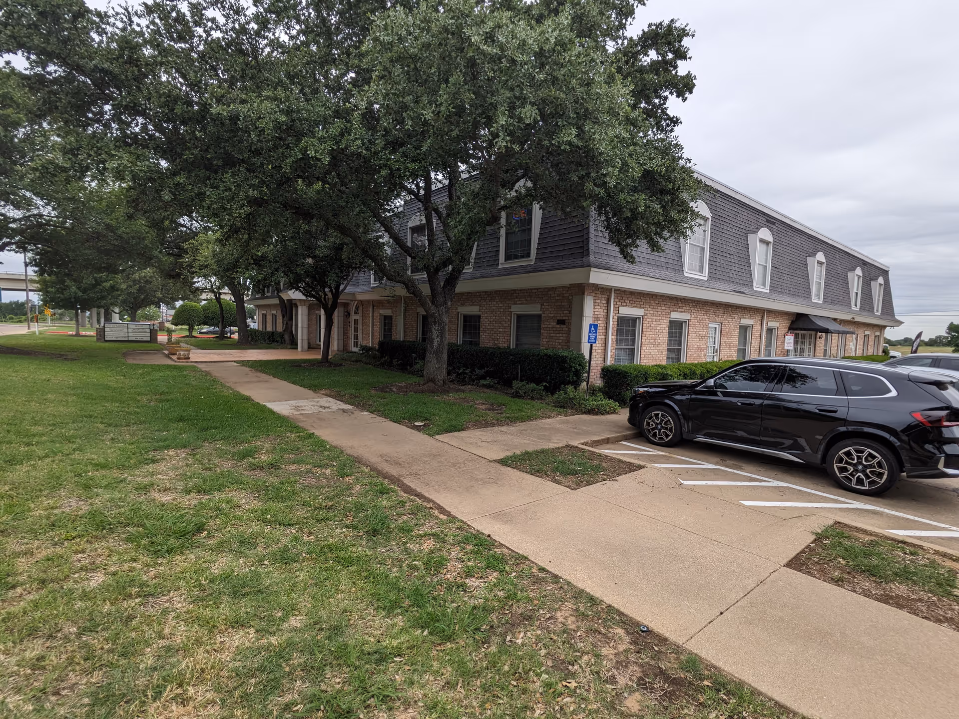 Exterior view of AccuAid Home Care building with brick walls, trees, and parked cars.