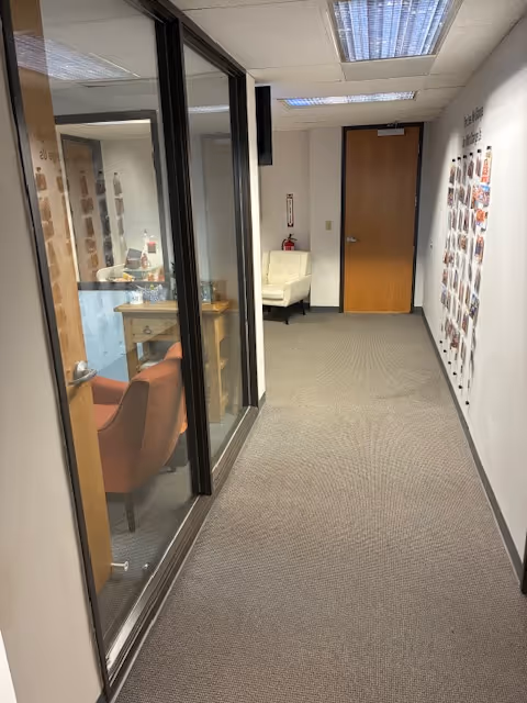 Interior hallway of a senior facility with glass-walled room and photo wall.
