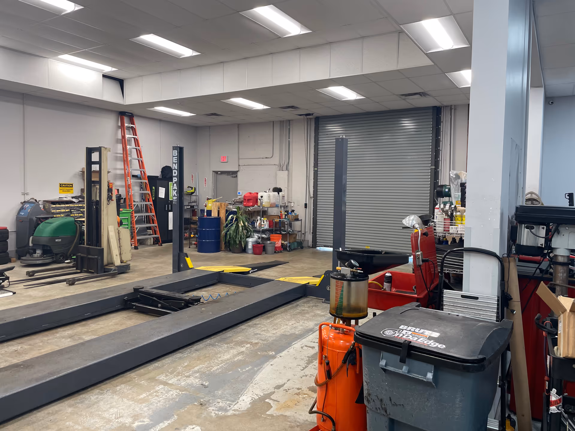 Industrial automotive workshop interior with car lifts, ladders, and various tools