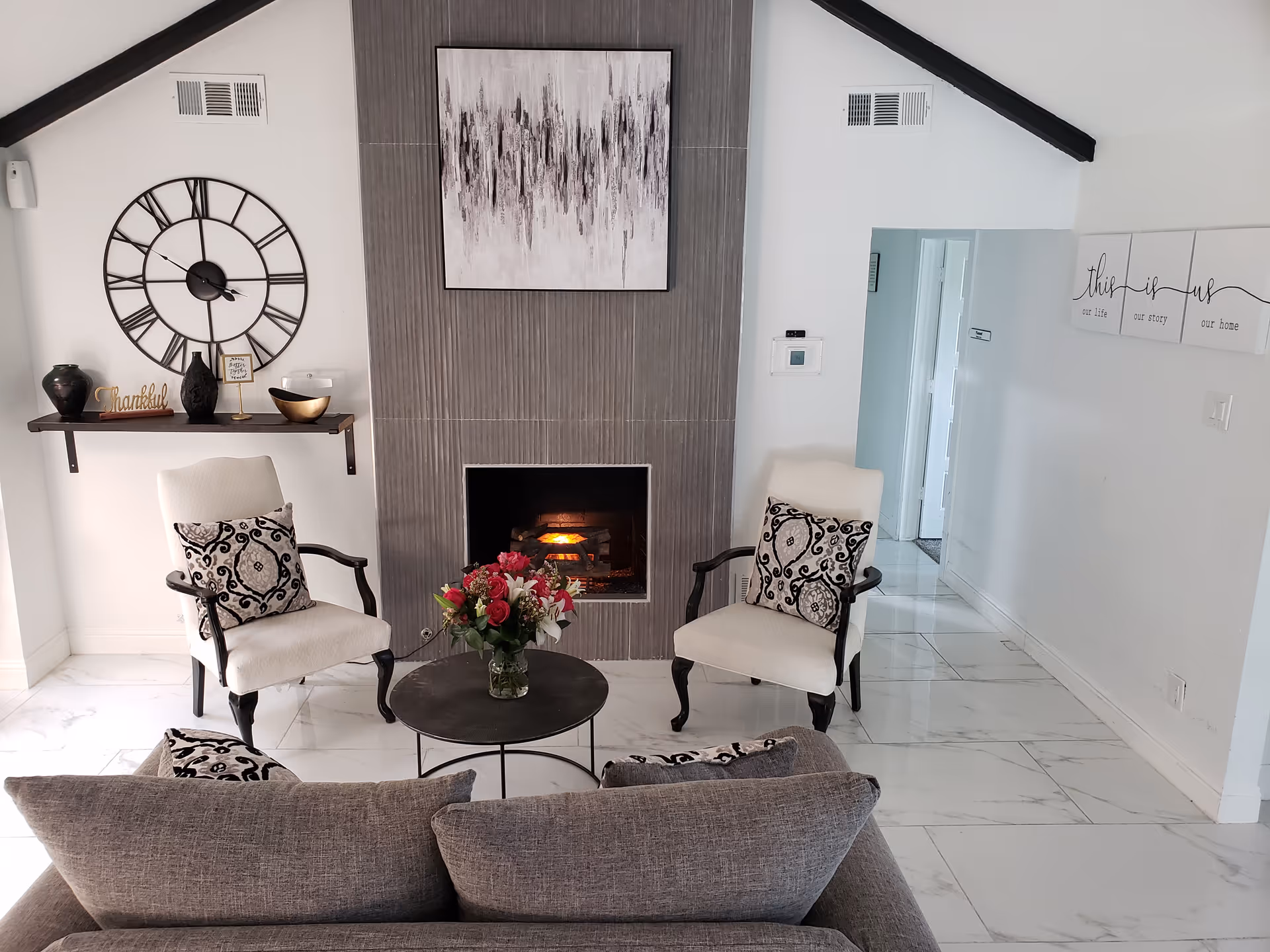 Cozy indoor living room with chairs, sofa, coffee table, and fireplace.