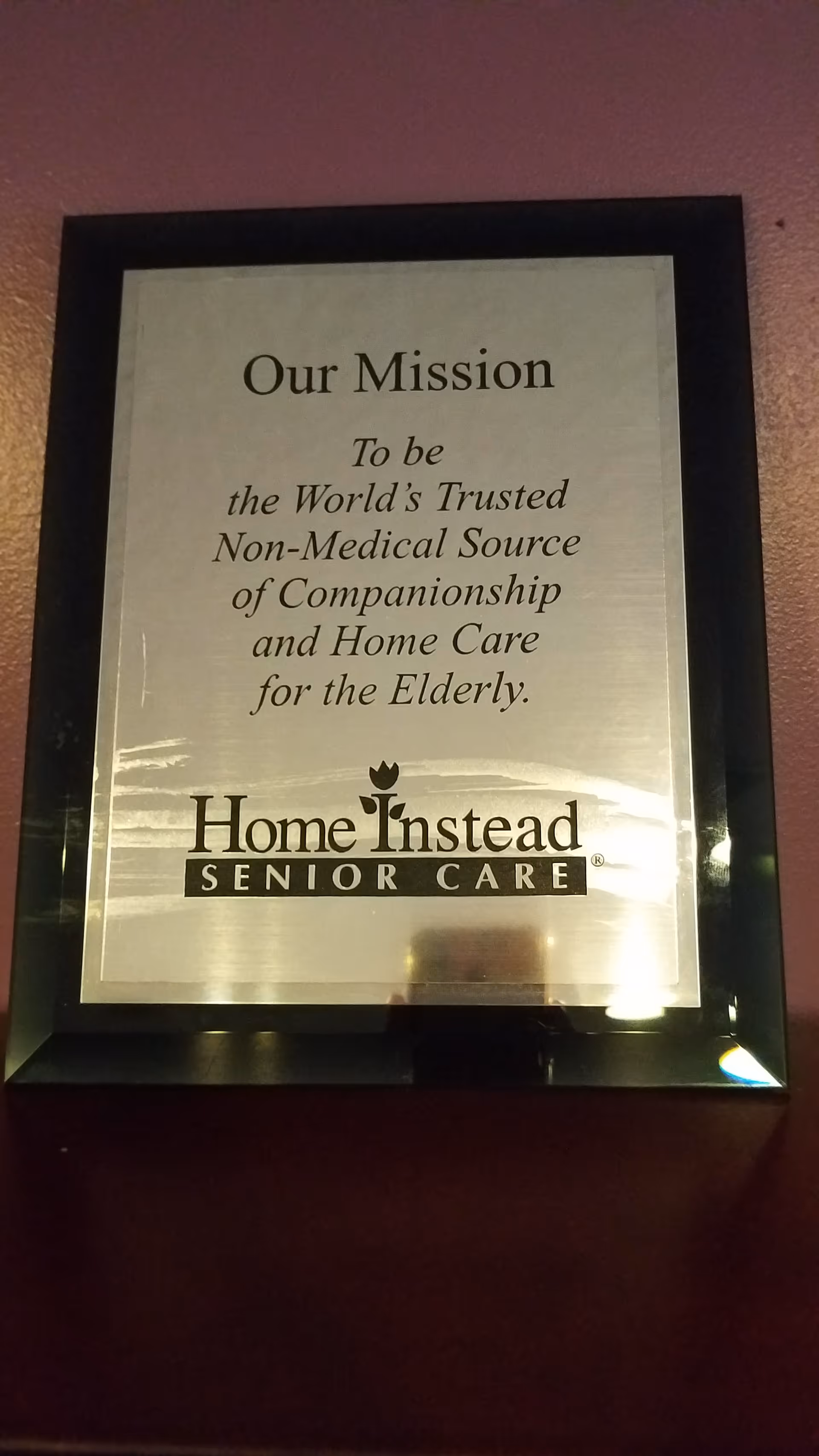 Framed plaque on a wall displaying Home Instead Senior Care mission statement.
