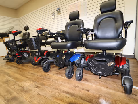 Row of mobility scooters lined up inside a facility's interior showroom.