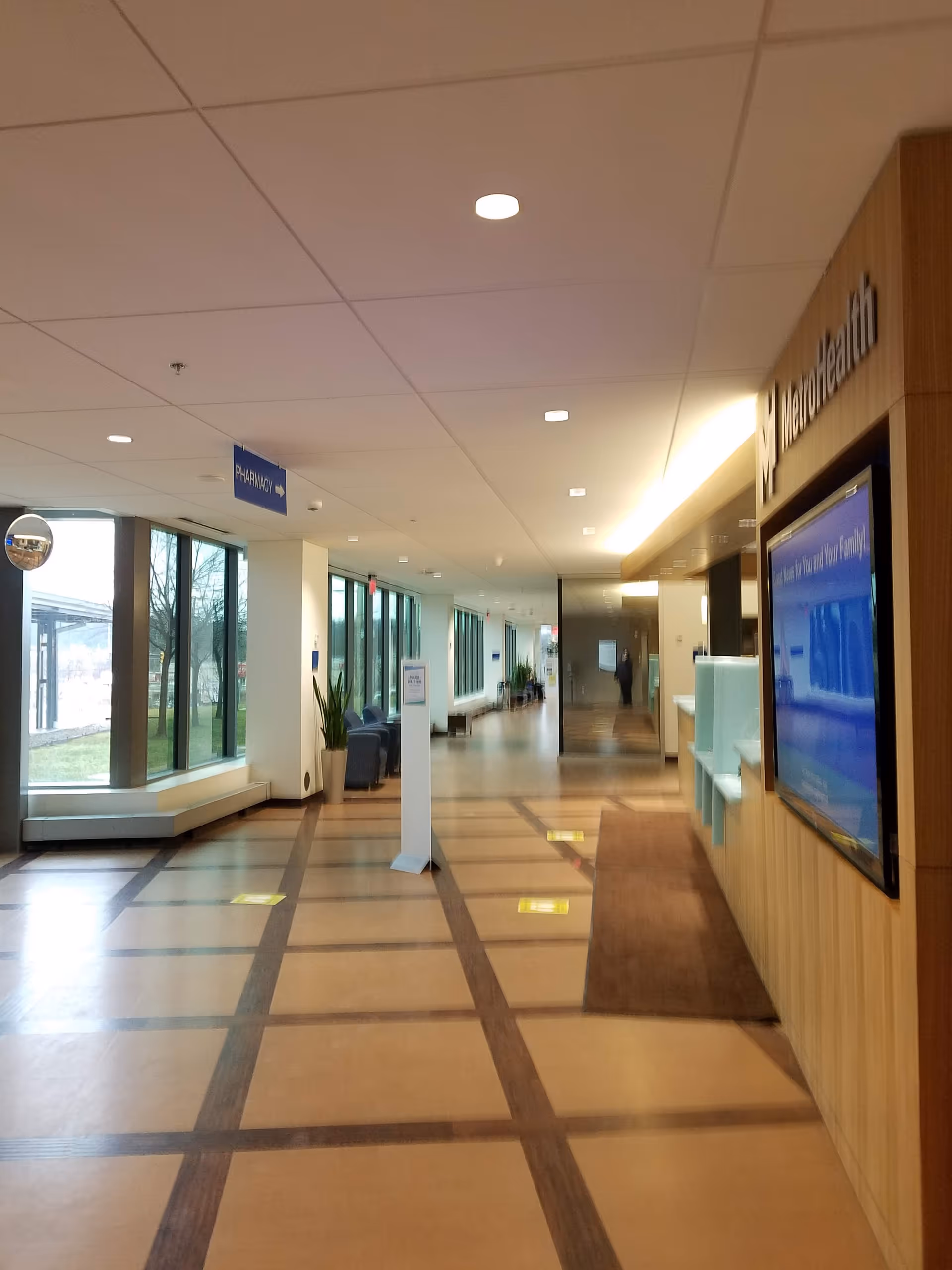 Bright interior corridor with seating, large windows, and a reception area along the right.