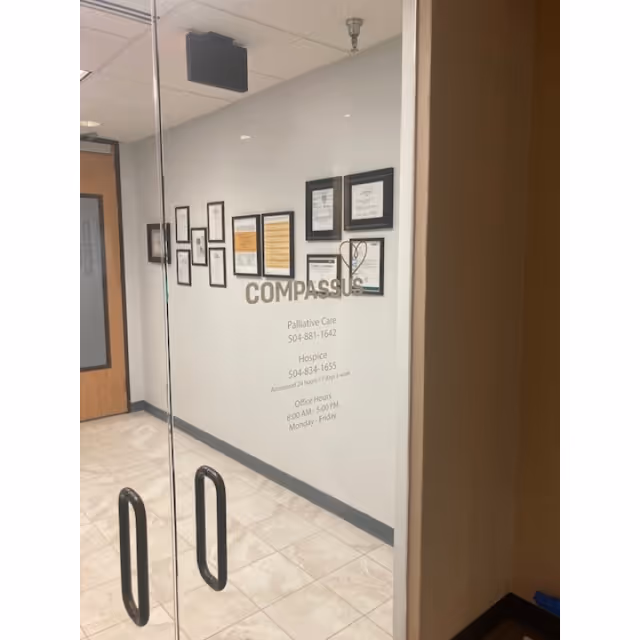 Glass doorway opening to a hallway with framed certificates and a Compassus sign.