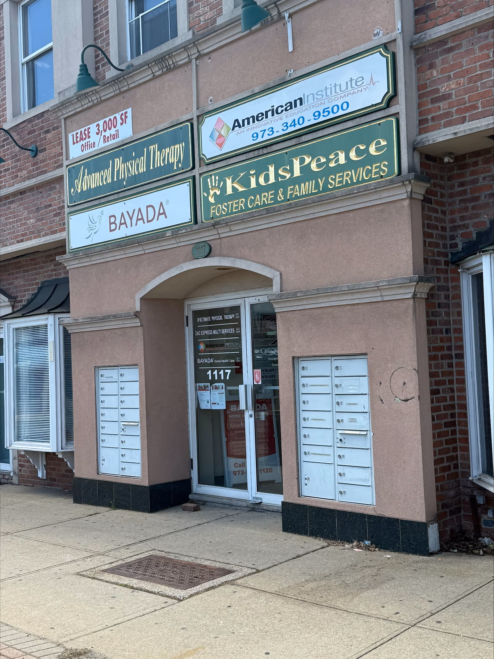 Two-story brick storefront with multiple signs including BAYADA and KidsPeace above a glass door.
