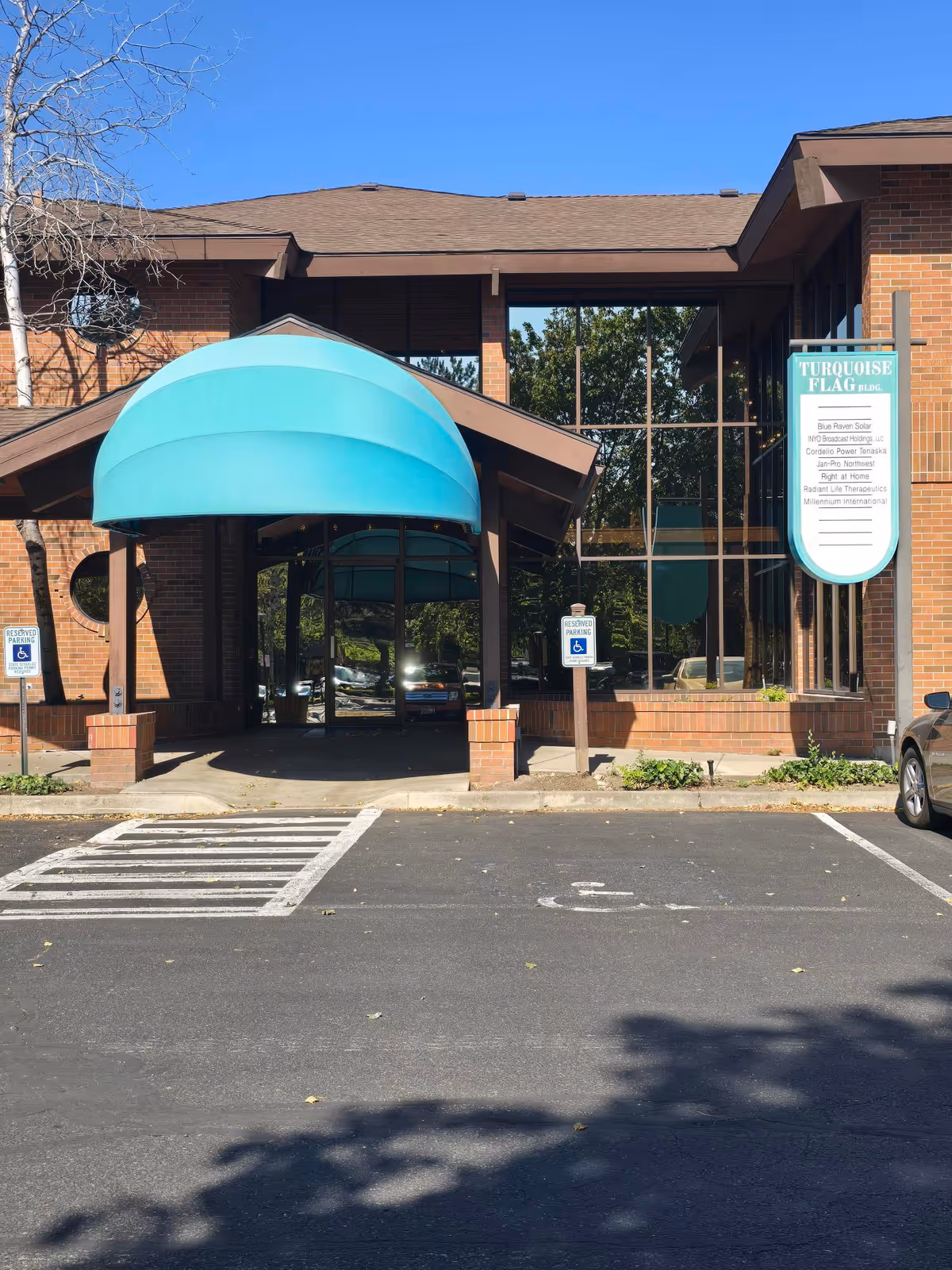 Brick facility entrance with glass walls and turquoise curved canopy.