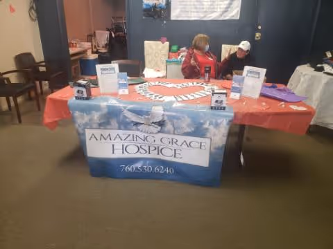 Two people sit at a table with an Amazing Grace Hospice banner