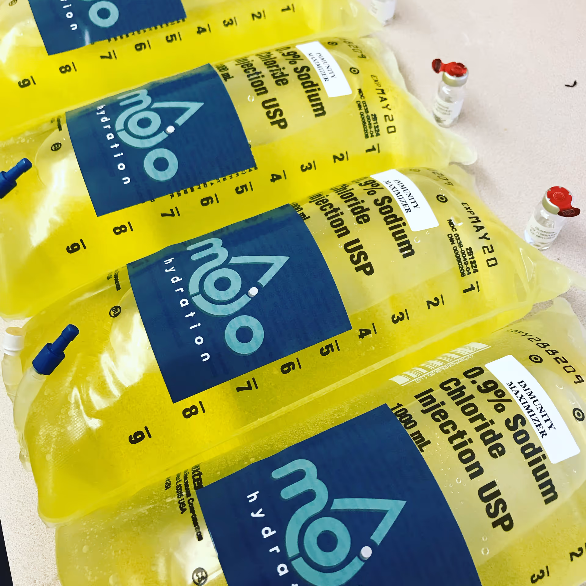 Bright yellow Mojo Health & Hydration IV bags with measurement marks on a clinical surface.