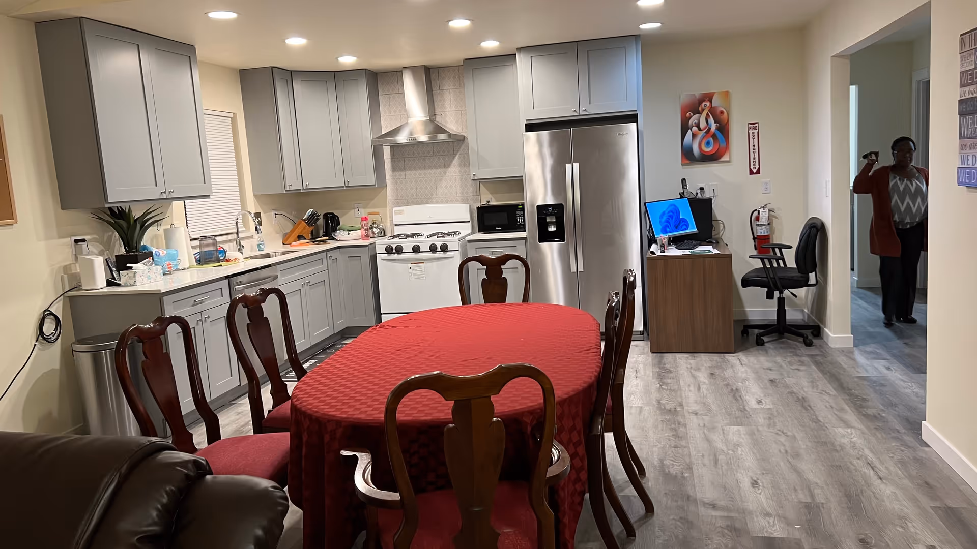 Kitchen and dining area in a senior home with gray cabinets and a red tablecloth.