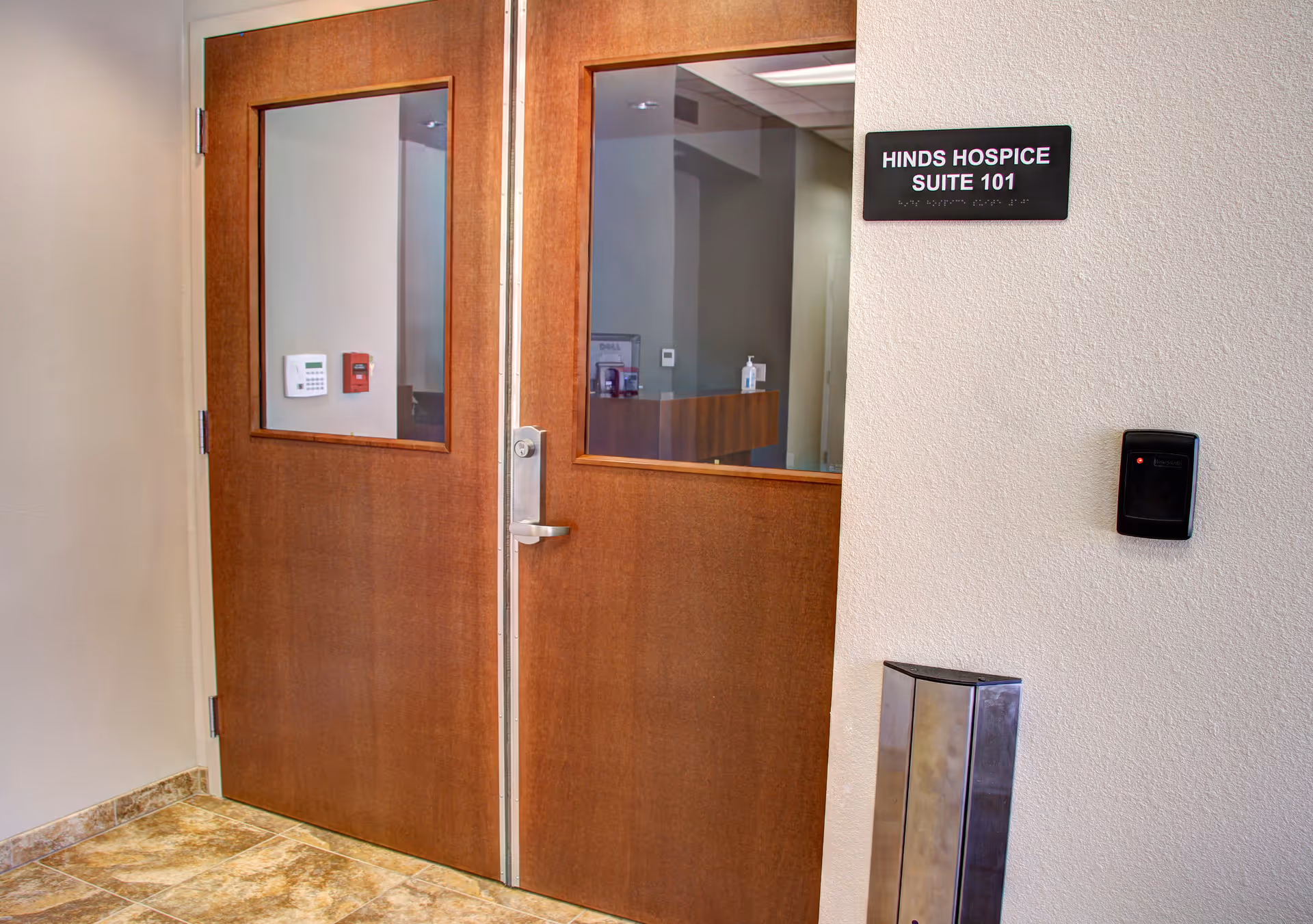 Wooden double doors lead to Hinds Hospice Suite 101 in a hallway interior.