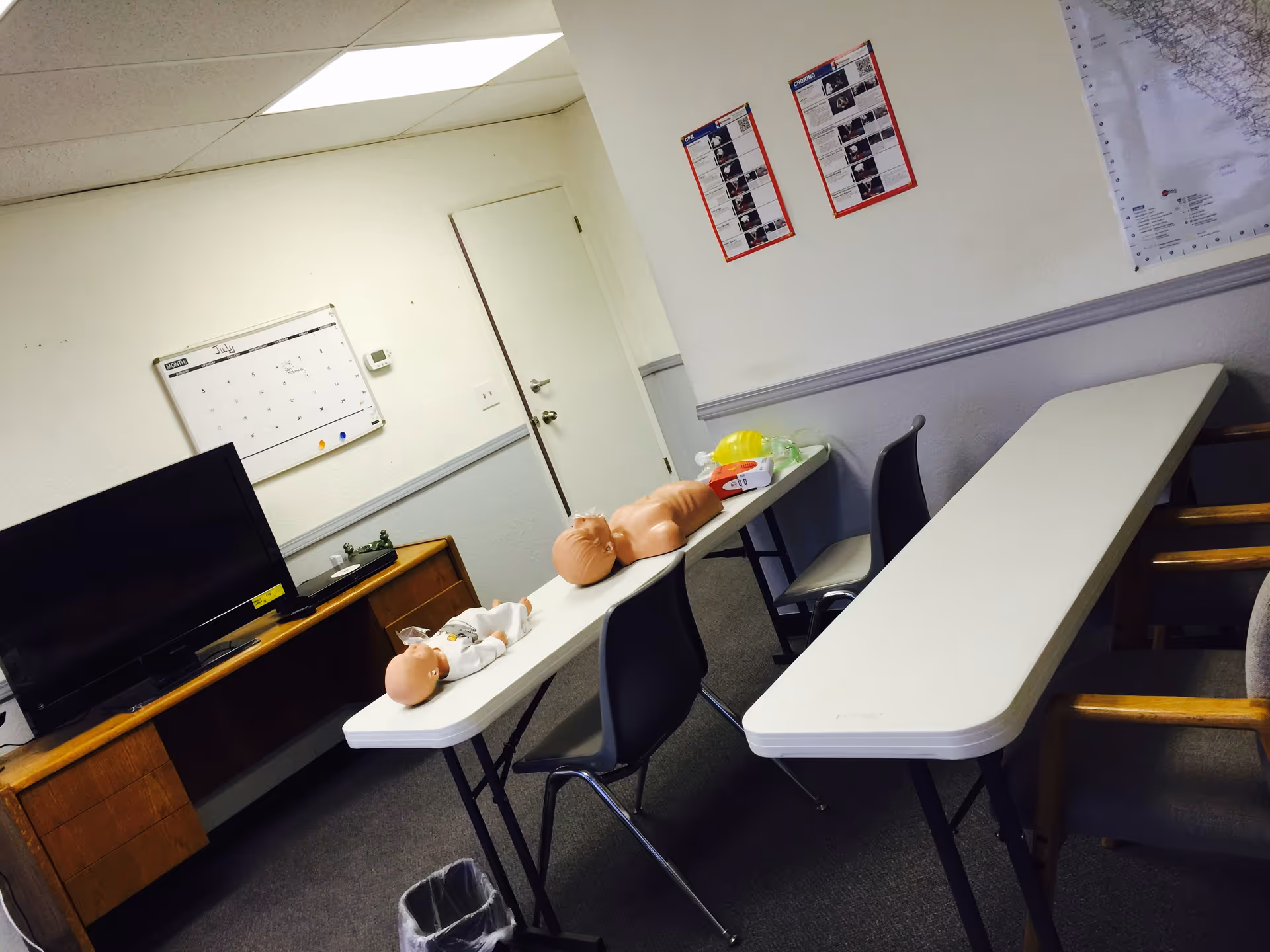 An interior training room with medical manikins on tables and a TV.