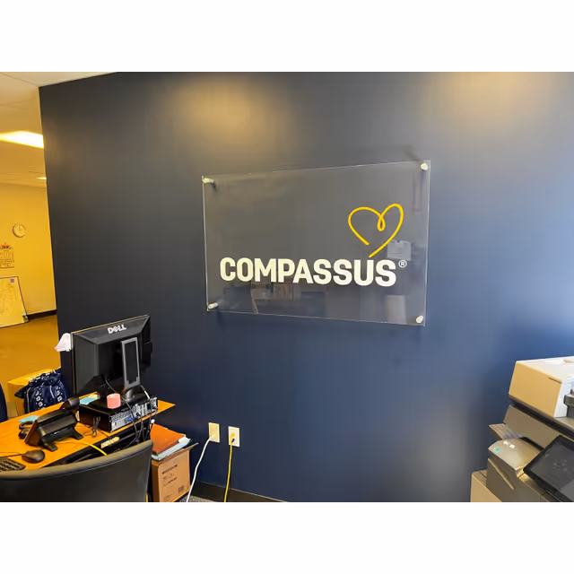 Reception area with a Compassus sign on a blue wall and office desk.