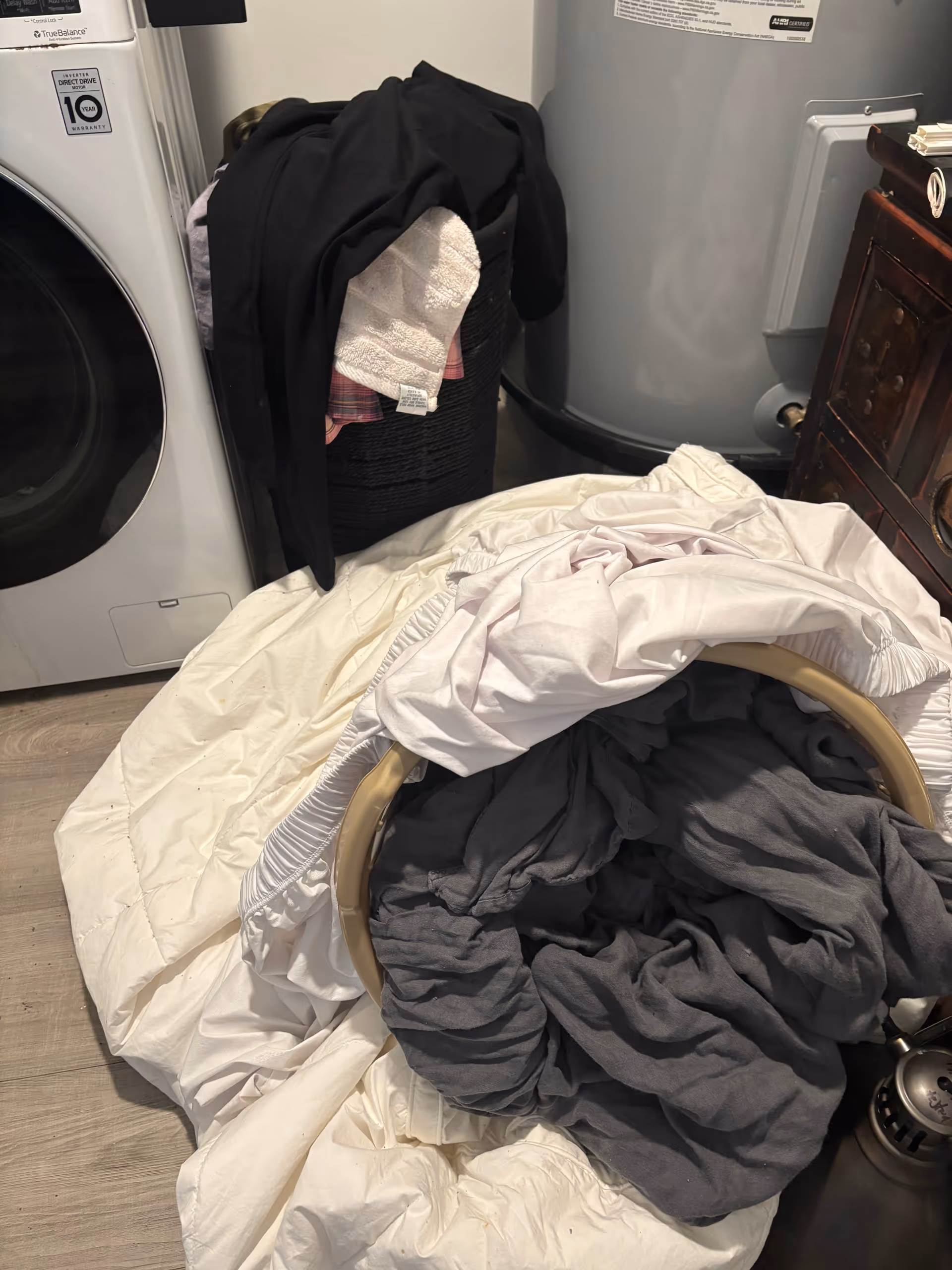 Laundry area with a front-loading washer, visible dryer, and clothes piled on a basket.