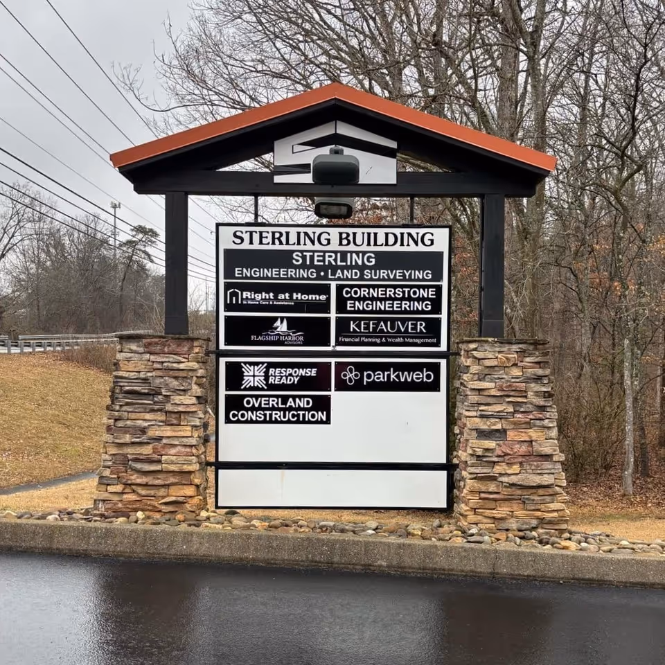 Outdoor sign structure with stone pillars displays Sterling Building and Right at Home logos.