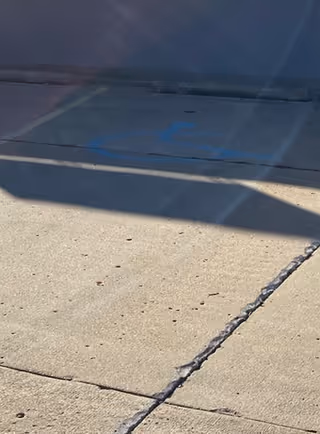 Close-up of a blue handicapped parking symbol painted on concrete.