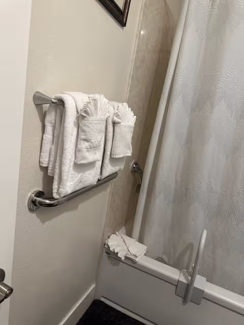 Bathroom scene with towels on a rack, grab bar, and curved shower curtain