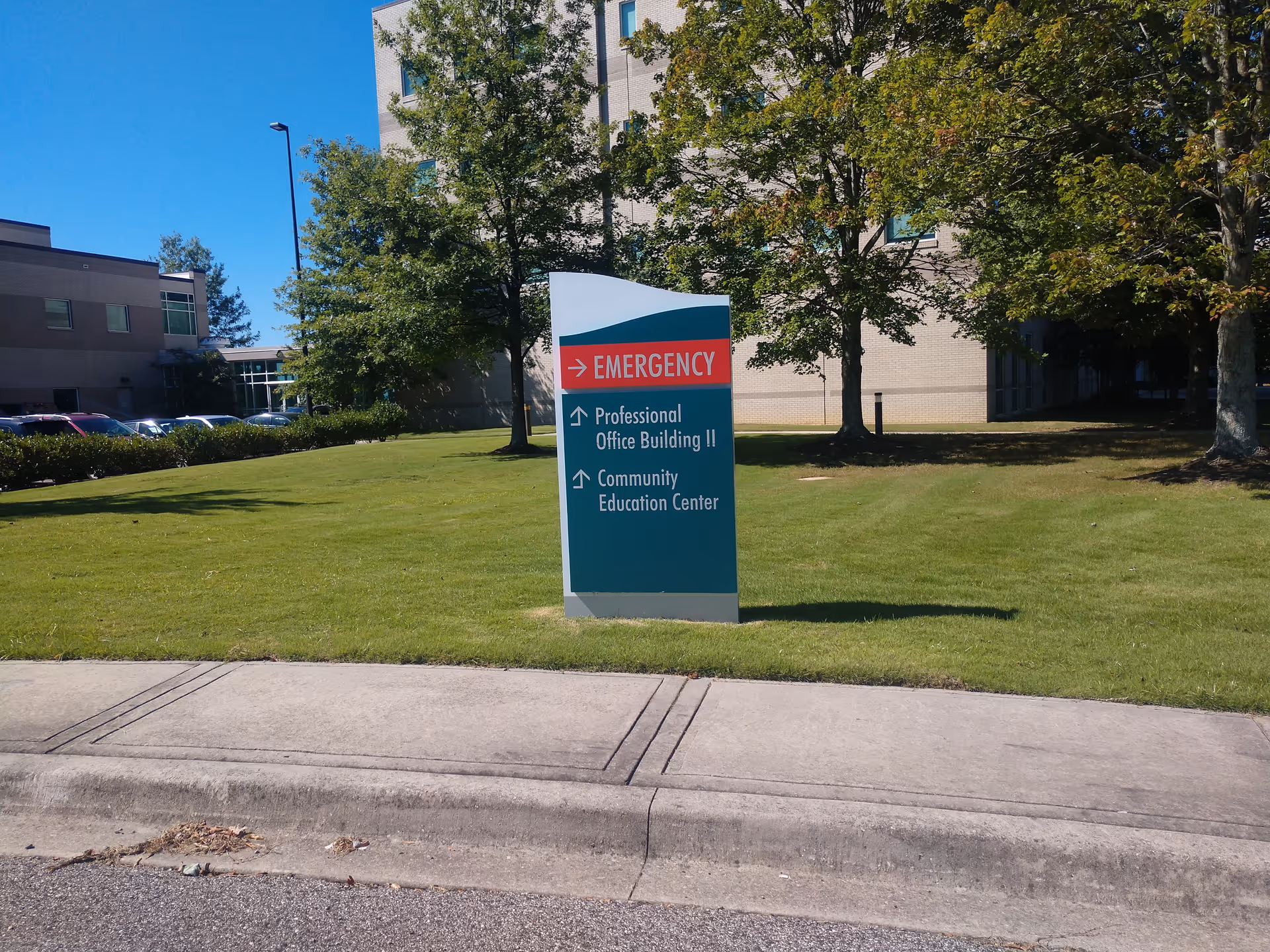 Exterior view of a medical center with a sign directing to Emergency and offices