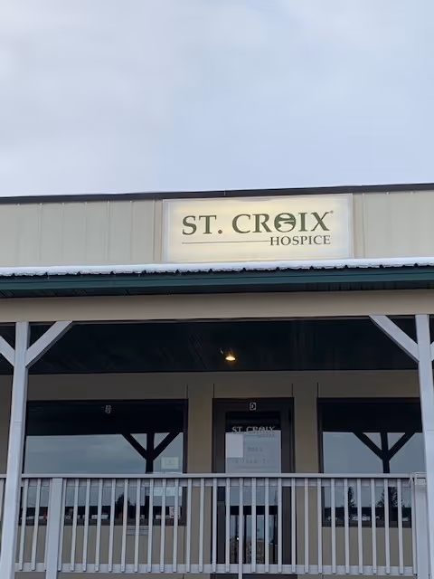 Front view of St. Croix Hospice building with sign, porch, and white railings.