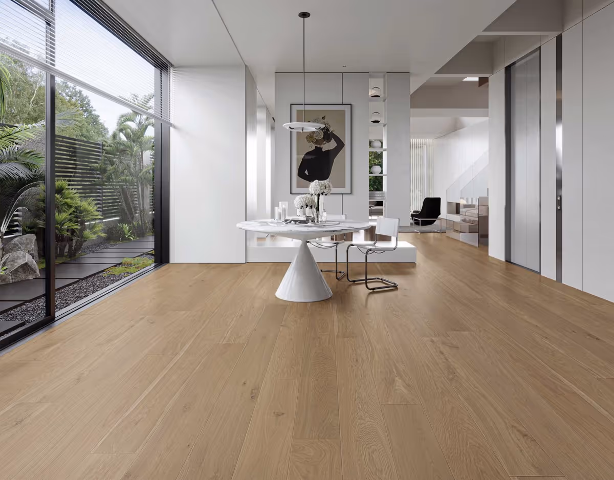 Modern, sunlit dining area with a round white table, chairs, and a view of a garden.