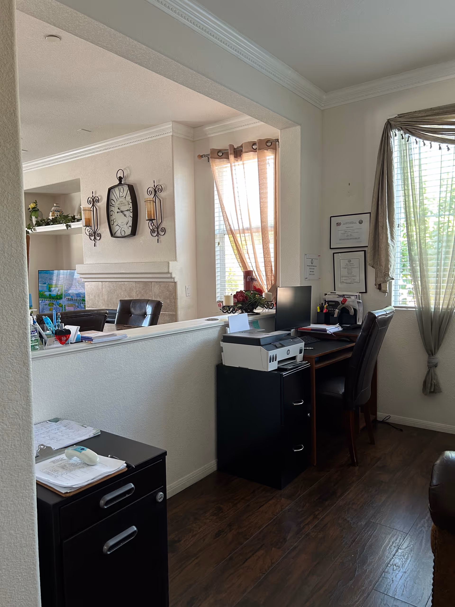 Interior of a reception area with a desk, computer, printer, and windows.