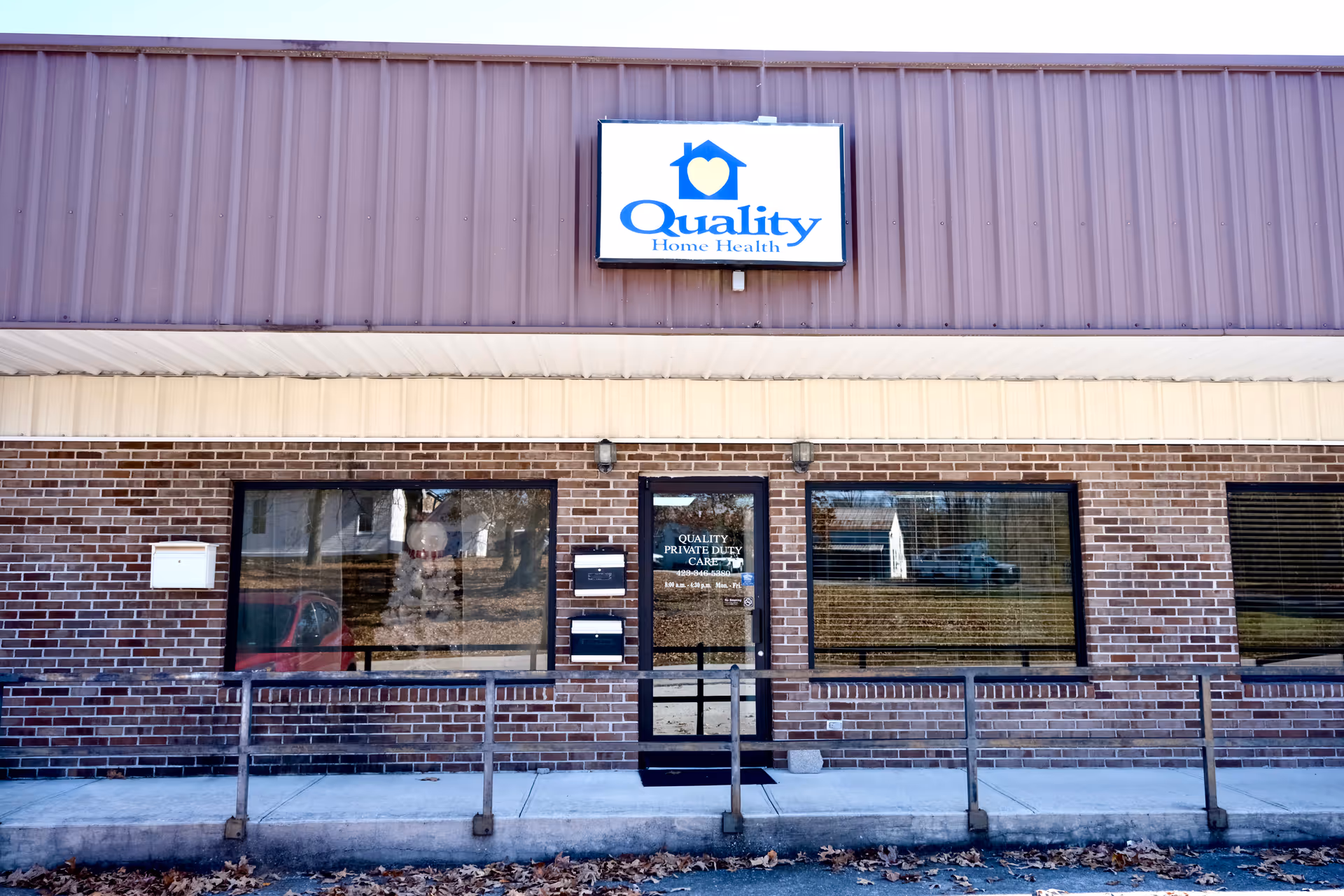 Brick building exterior with a Quality Private Duty Care sign above glass doors.