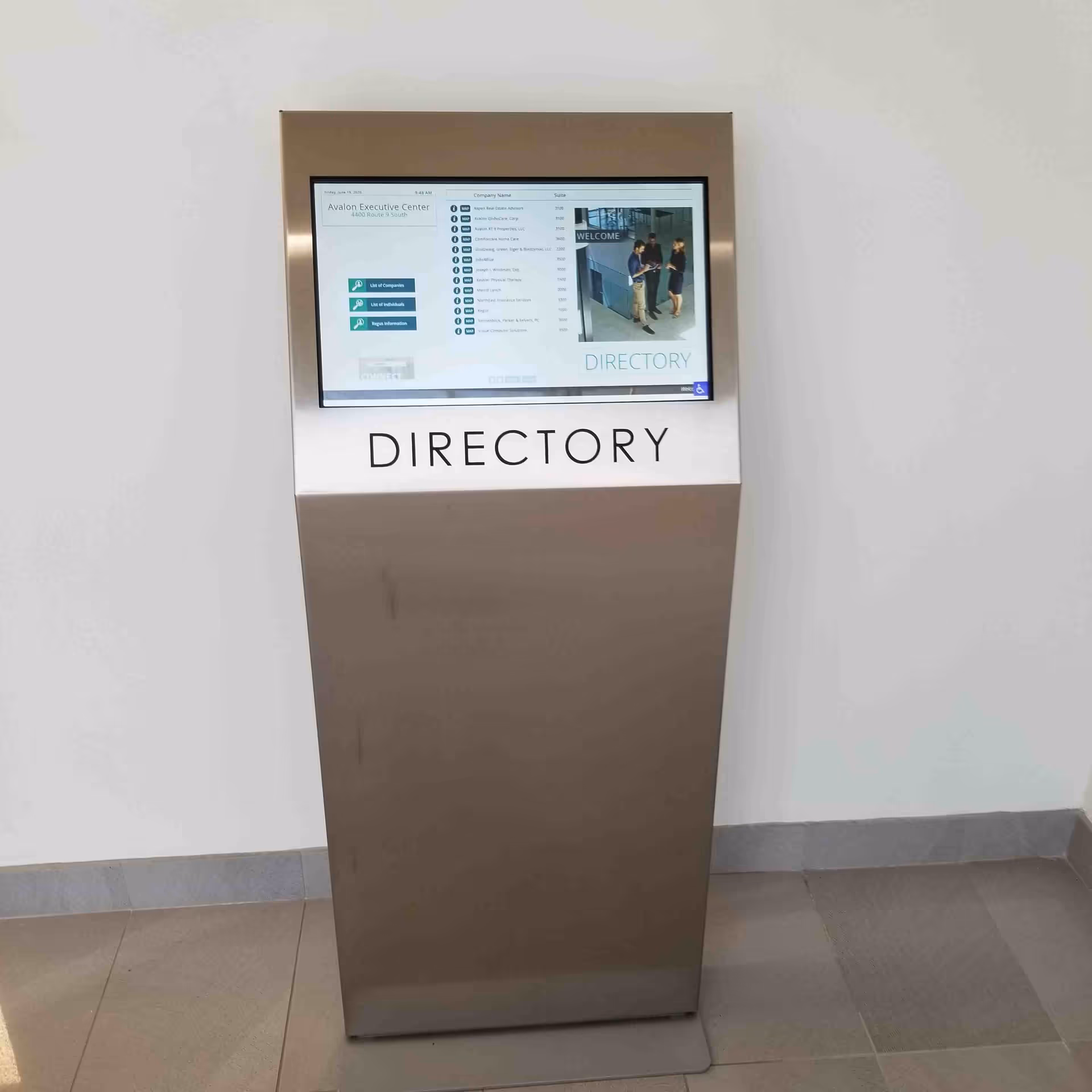 Metal directory kiosk with touchscreen display in a hallway.