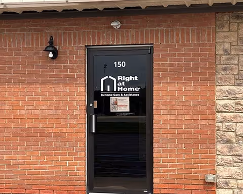 Brick building exterior with a glass door displaying the Right at Home logo and address 150.