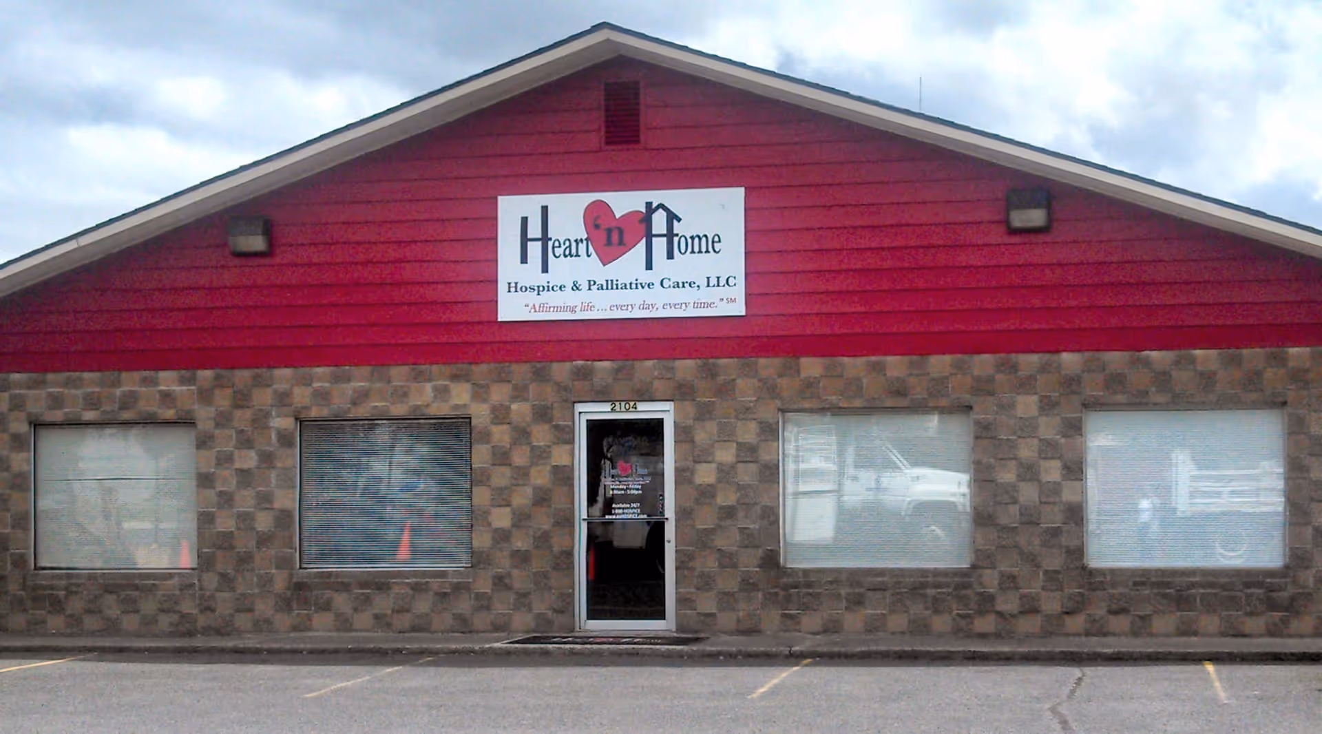 Front view of a red-roofed building with a Heart 'n Home Hospice sign.