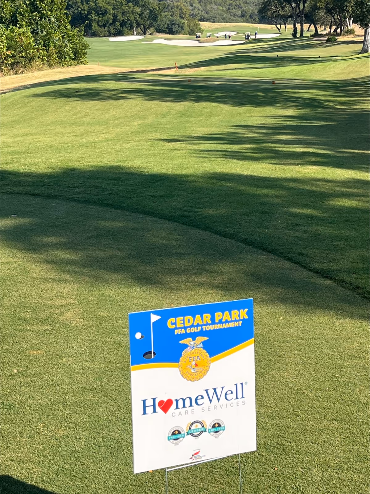 Outdoor golf course with a Cedar Park sign advertising HomeWell Care Services.