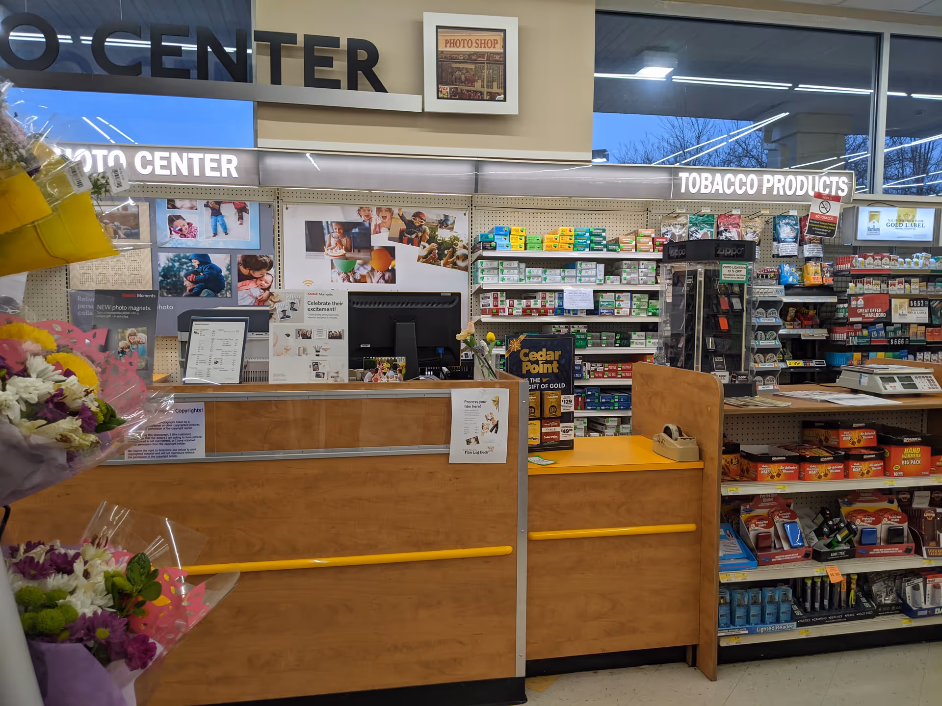 Interior drugstore checkout area with product shelves and bouquets near the counter.