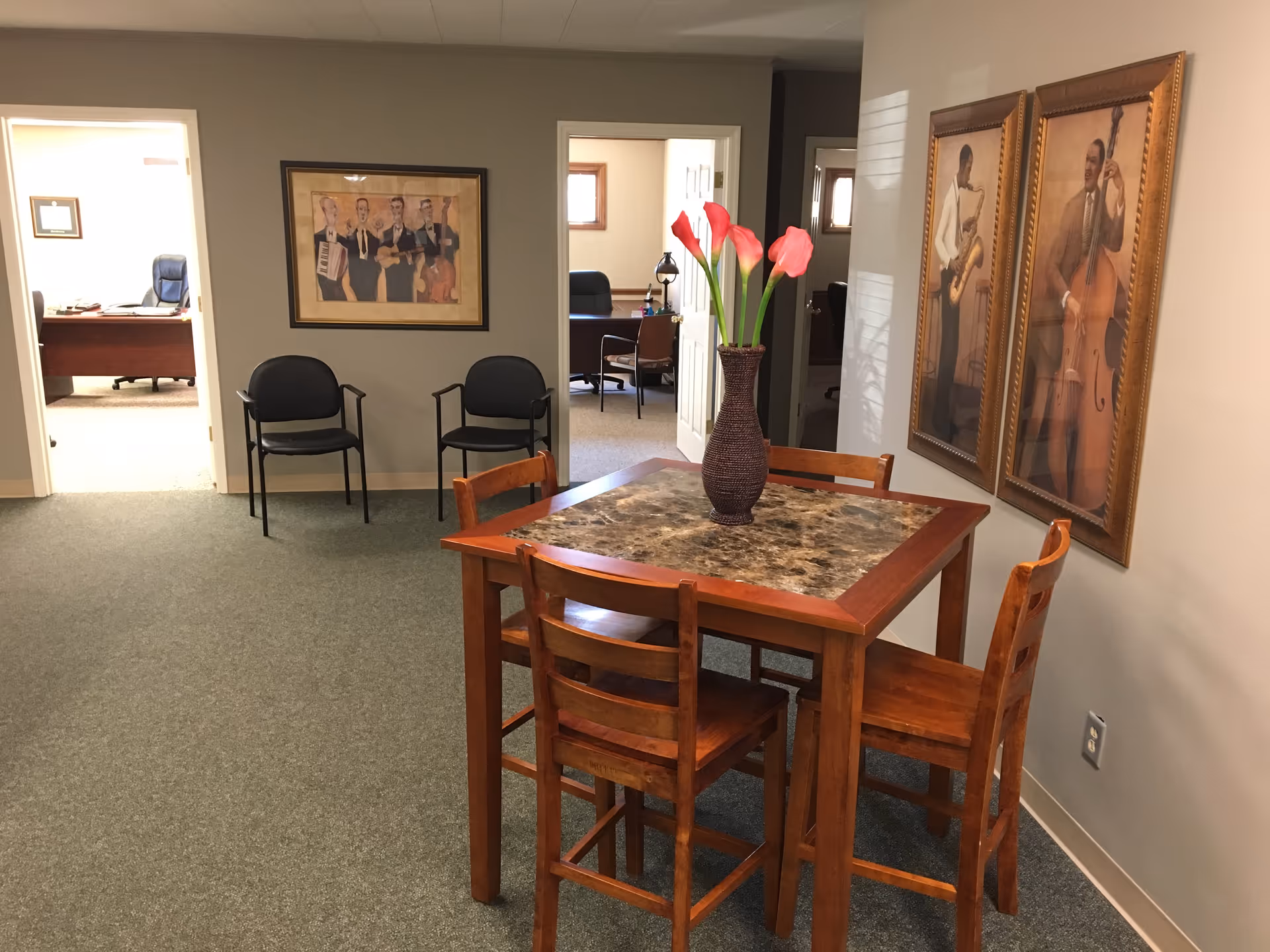 A wooden dining table with four chairs and a vase of flowers in a hallway.