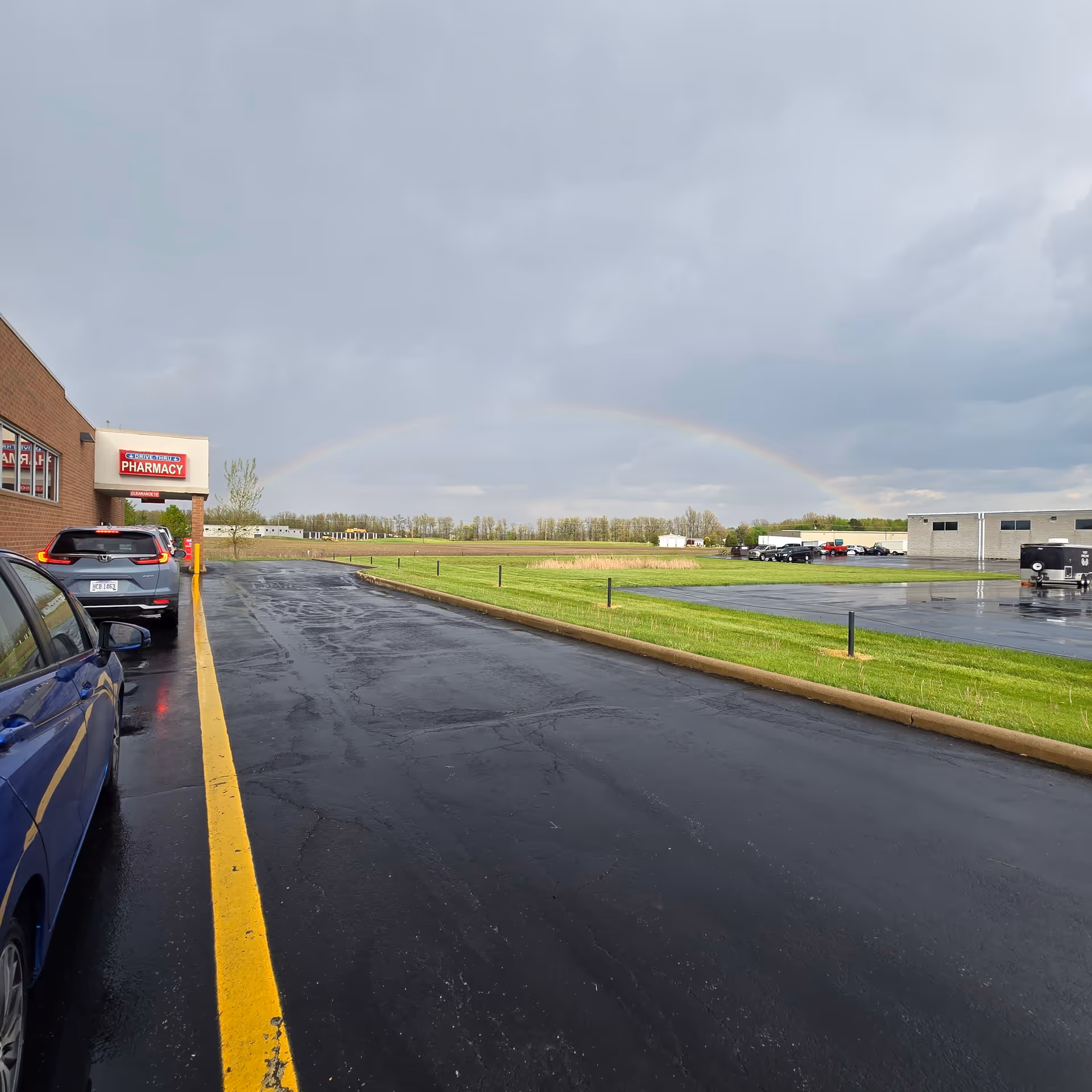 Exterior view of a Discount Drug Mart entrance with a rainbow over the parking lot.