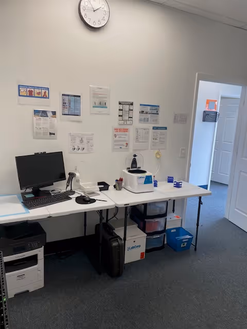 Office desk with computer, printer, and medical equipment in a clinic room.