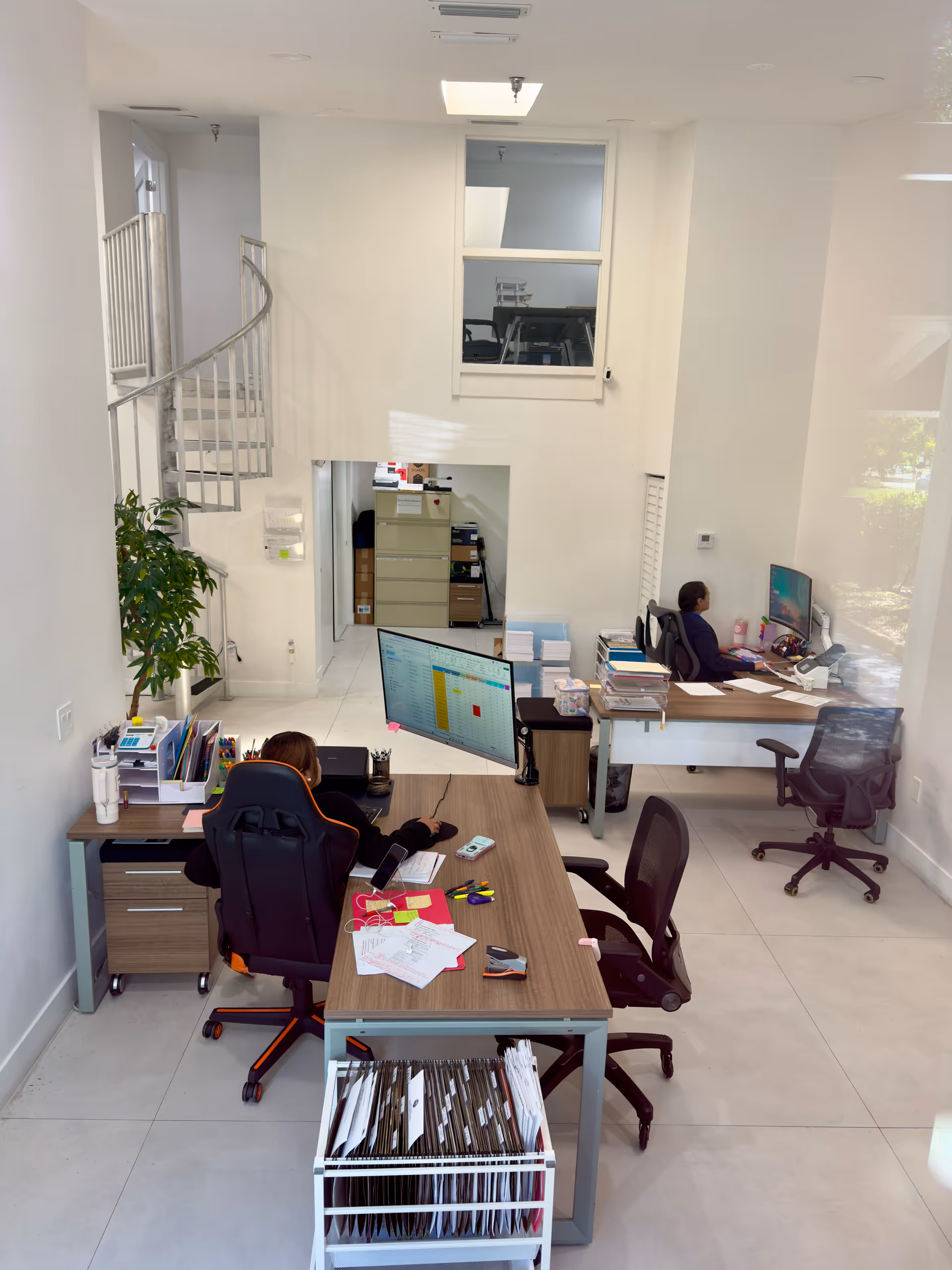 Office workspace inside the facility with two staff at desks and computers.