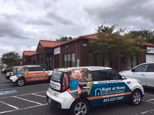 Brick storefront with a Right at Home building and branded service vans in the parking lot.