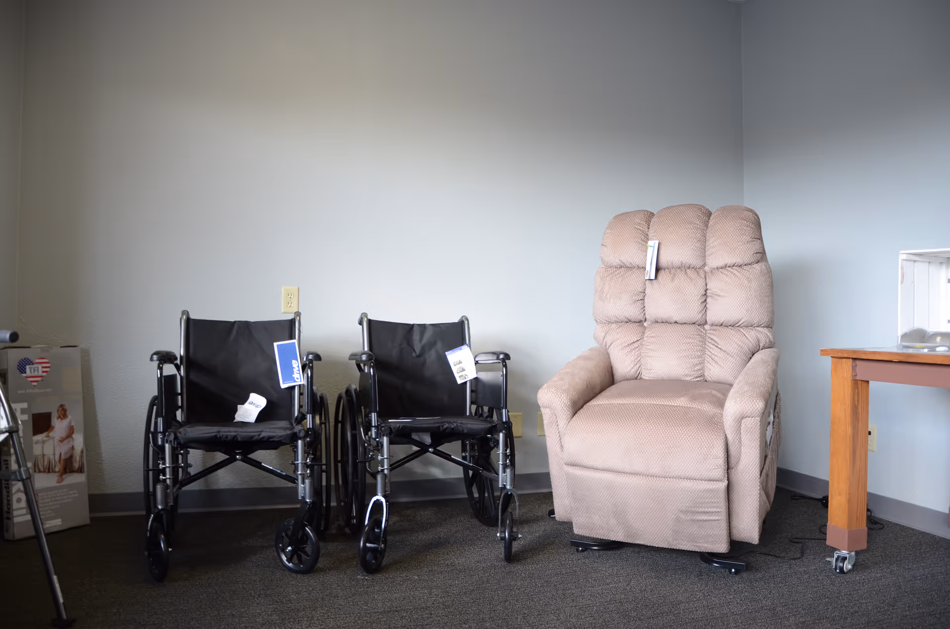 Two wheelchairs and a beige recliner sit in a small interior room at Promedcare.